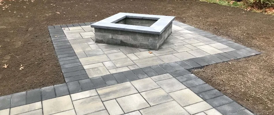 Dirt around a paver patio in Quincy, MA, with a fire pit.