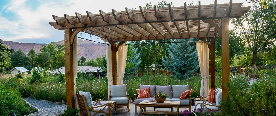 Wooden pergola with furniture underneath it on a property in Boston, MA.